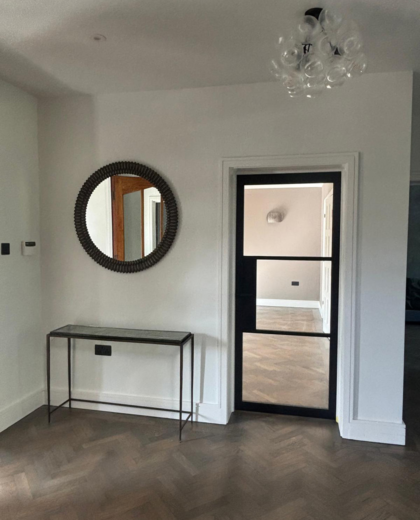 Renovated hallway with herringbone floor and black-framed glazed door – renovating a Victorian or Edwardian house